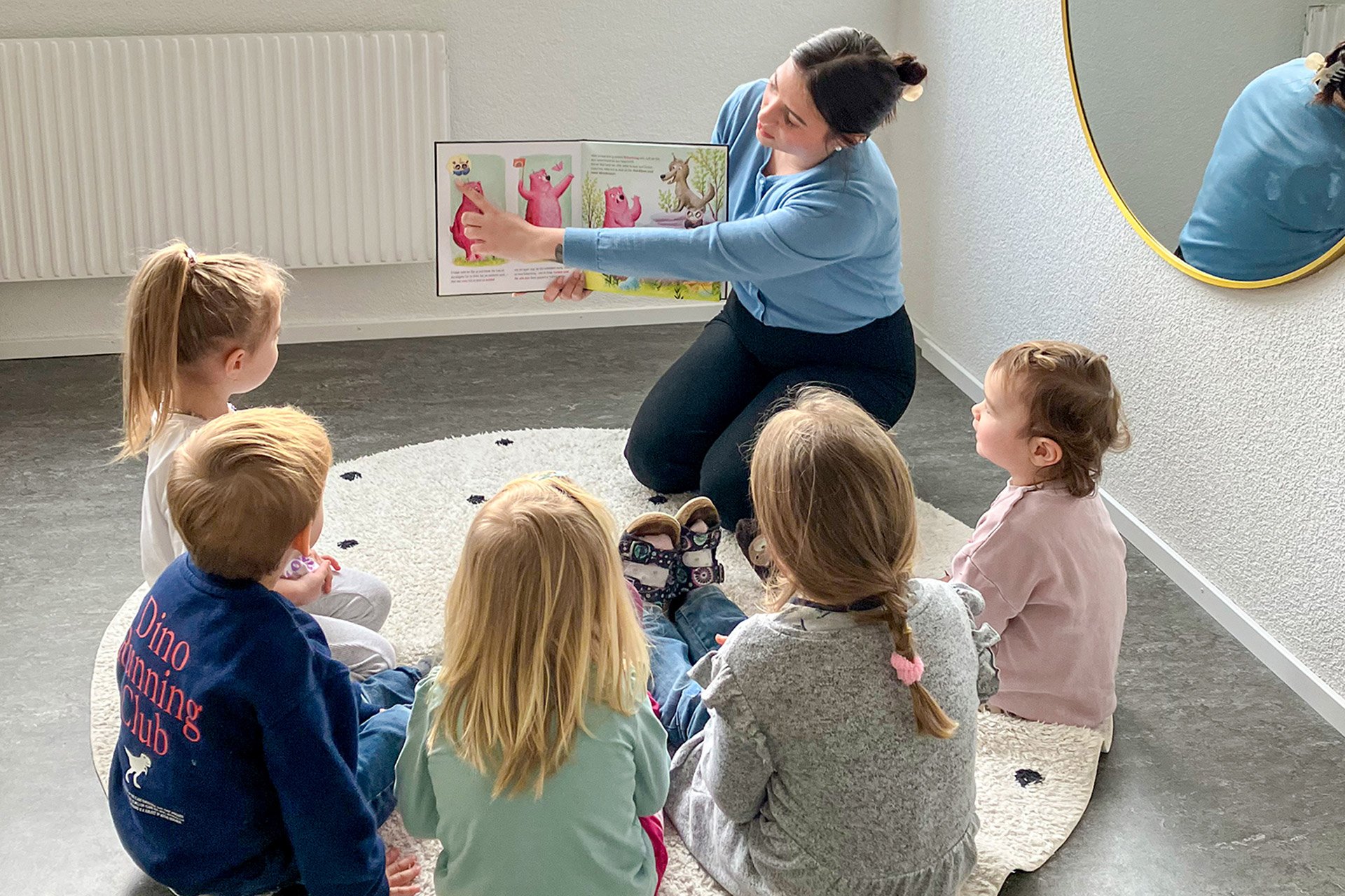 Kita kidsco Gümligen Betreuerin liest Büchli Kindern vor