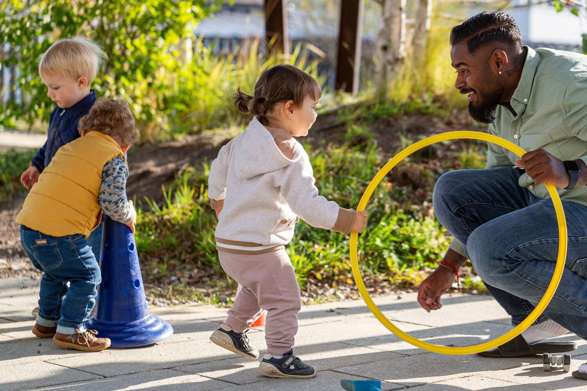 Kita kidsco City Kitaleiter spielt mit Kindern draussen