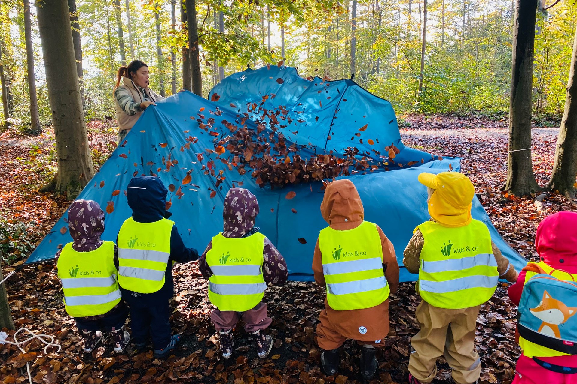 Kita kidsco Europaalle Kinder spielen mit Blätter im Wald