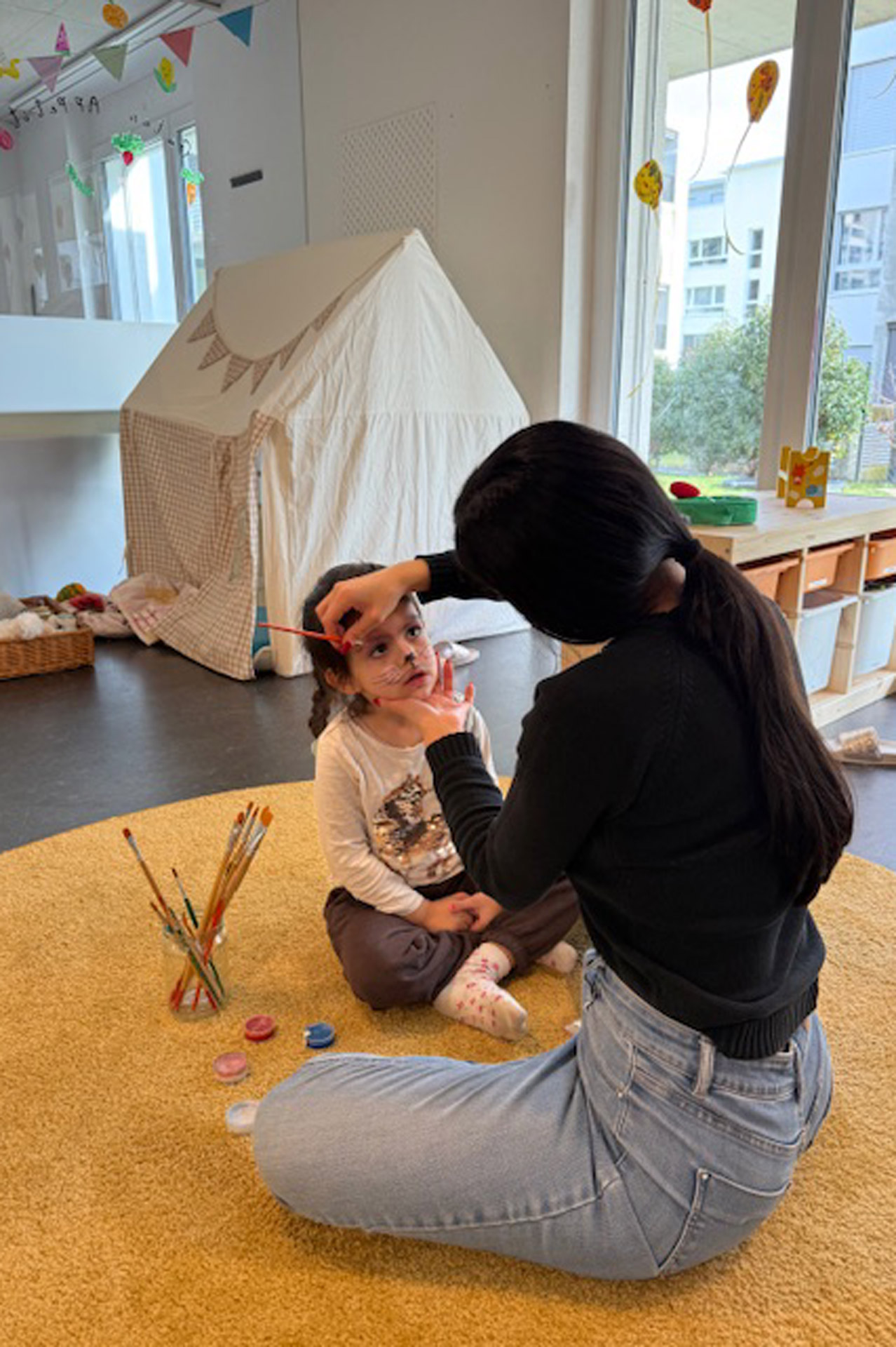 Kita kidsco Bözingen Betreuerin schminkt ein Kind in der Kita