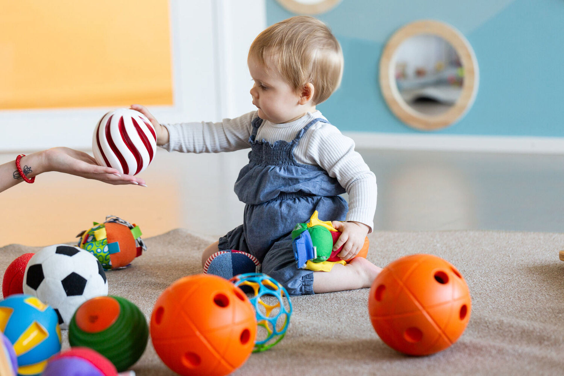 Kita kidsco City Kleinkind erhält Ball von Betreuerin