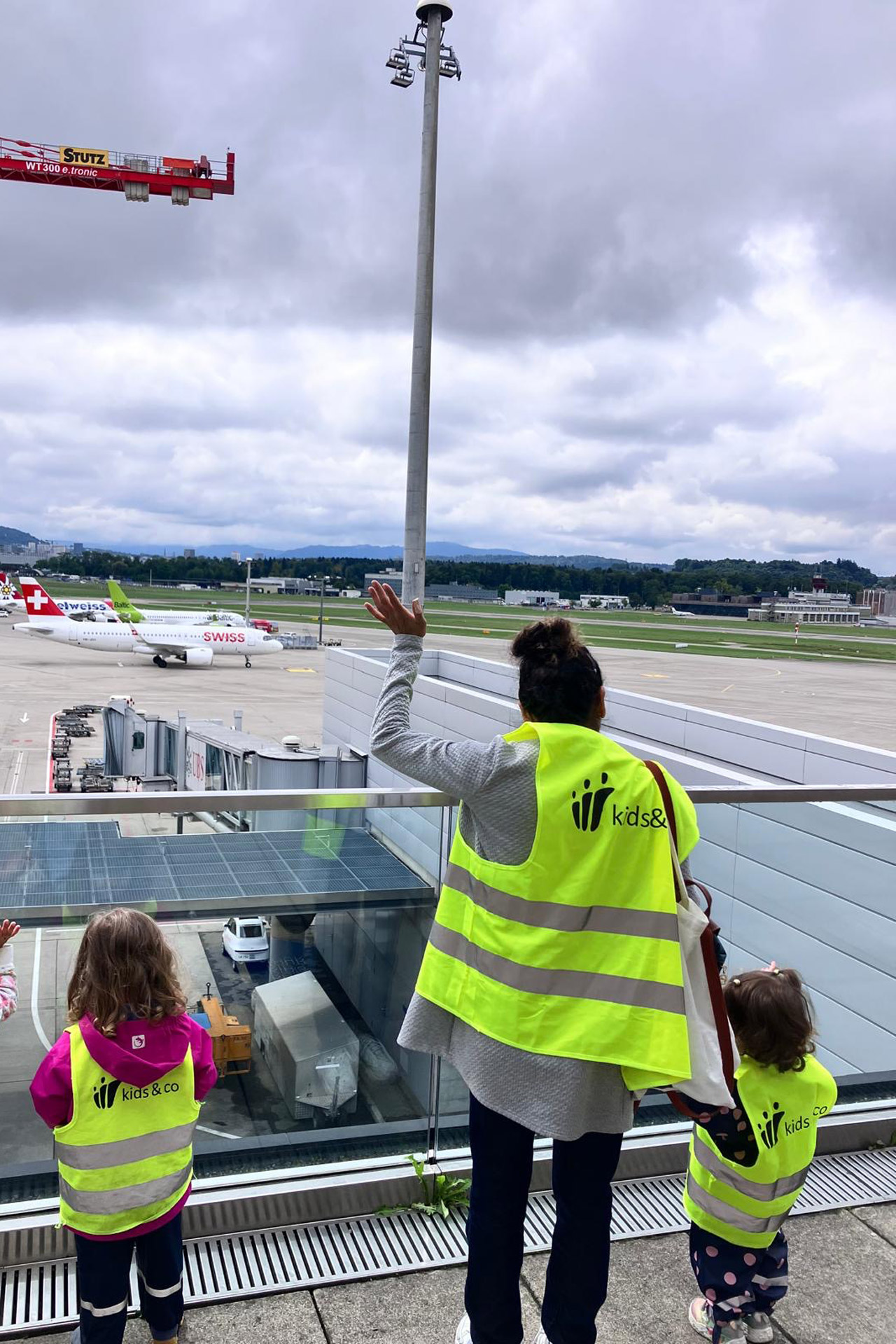Kita kidsco Tiergarten Kinder und Betreuerin wünschen Flugzeugen einen guten Flug am Flughafen Zürich