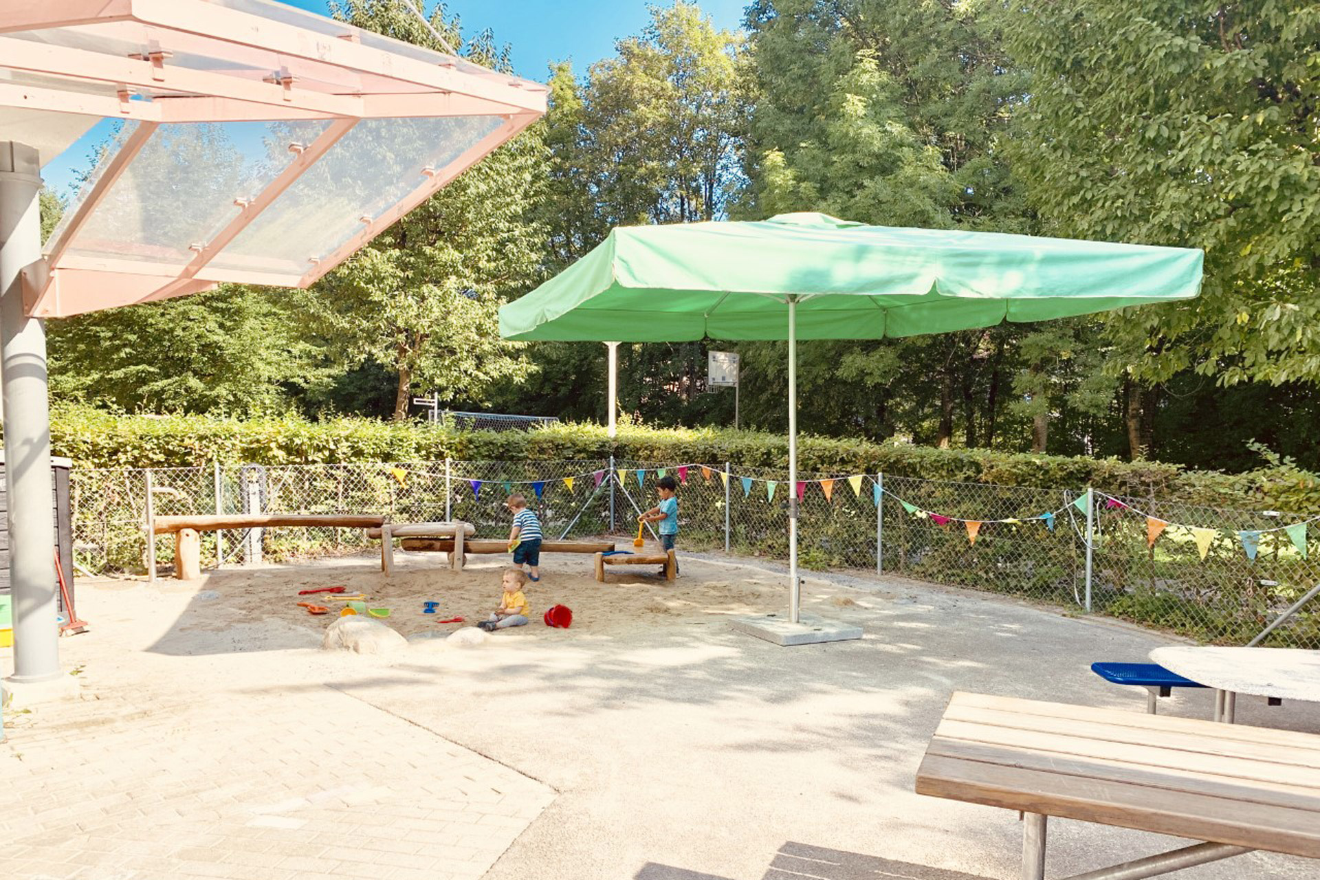 Kita kidsco Tiergarten Aussenbereich der Kita mit Sandkasten und Schutz gegen Sonne