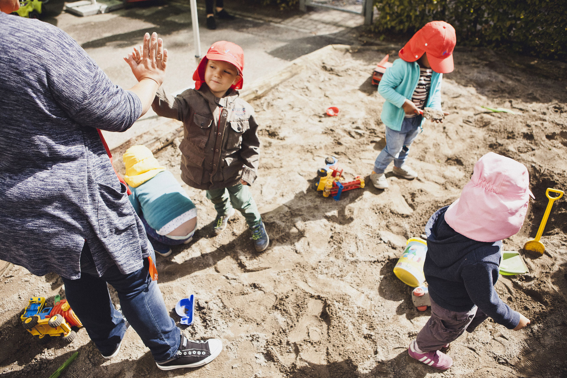 Kita kidsco Tiergarten Kind gibt Betreuer ein High-Five im Sandkasten